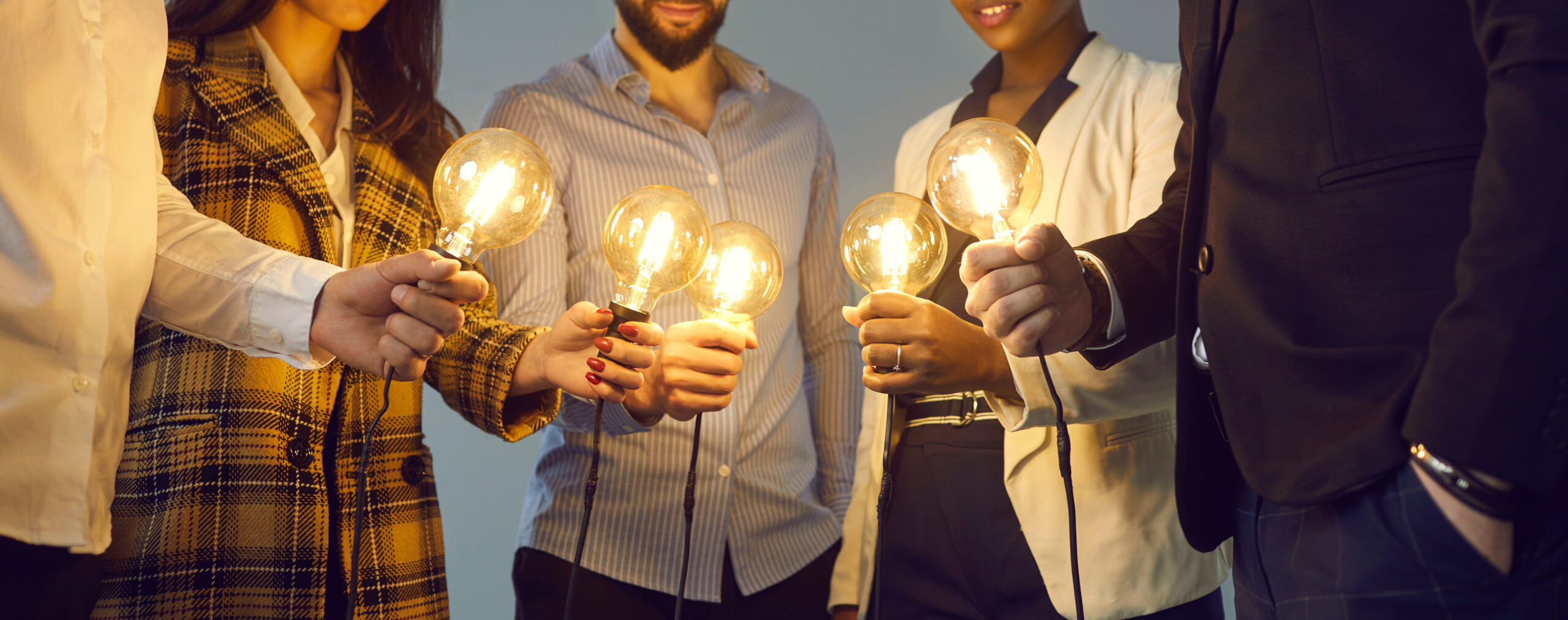 Achtergrond met een team dat gloeiende vintage Edison gloeilampen vasthoudt.